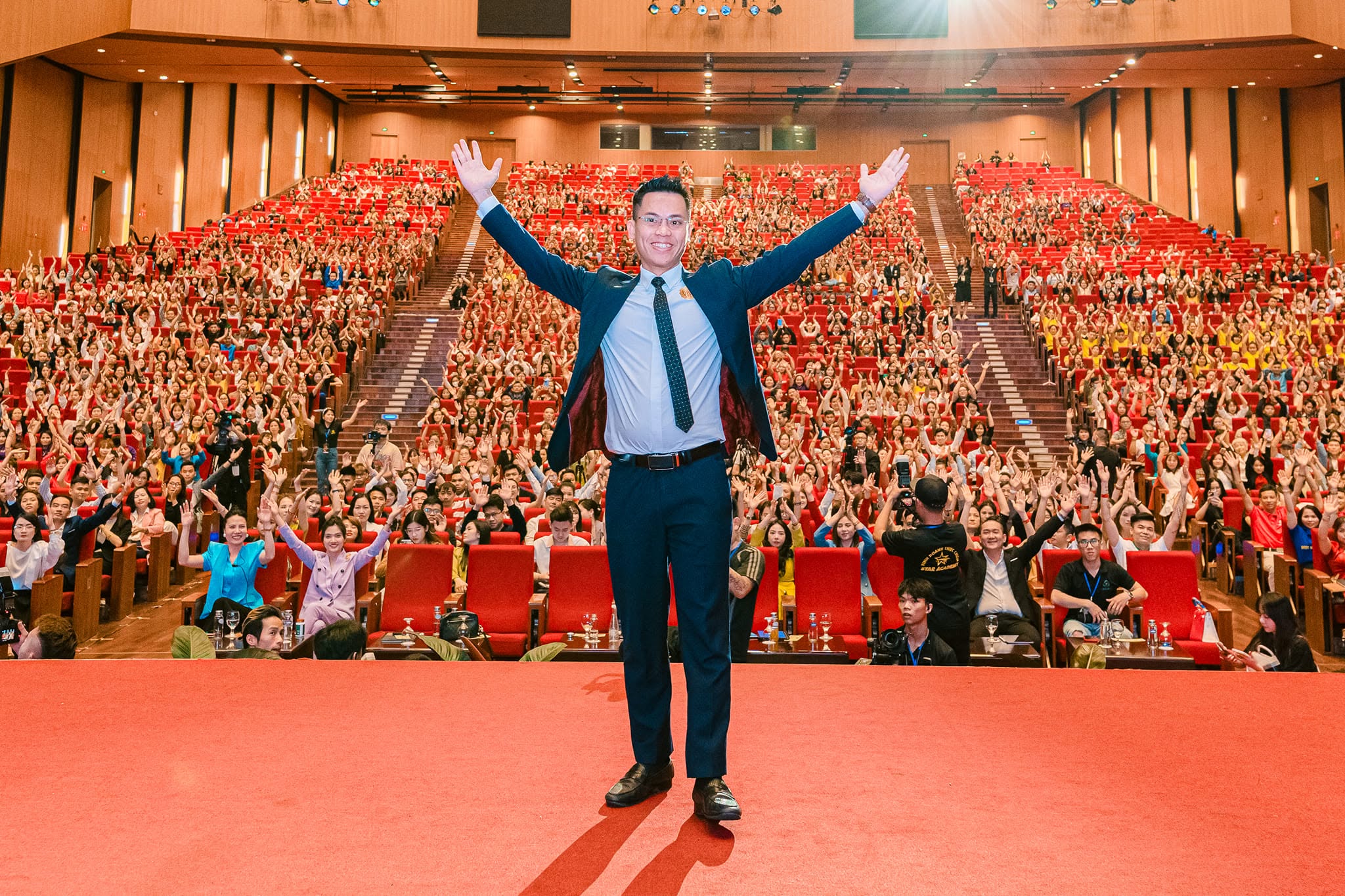 Anthony Lee trên sân khấu, dang tay chào hàng nghìn học viên trong hội trường